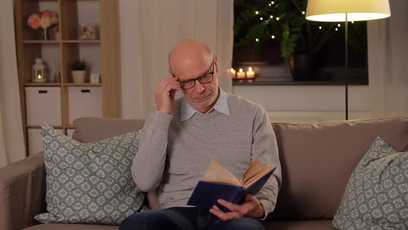 Bald Senior Man on Sofa Reading Book at Home