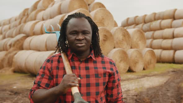 Portrait of Young African Farmer with Pitchfork Over His Shoulder Nodding His Head As Approval