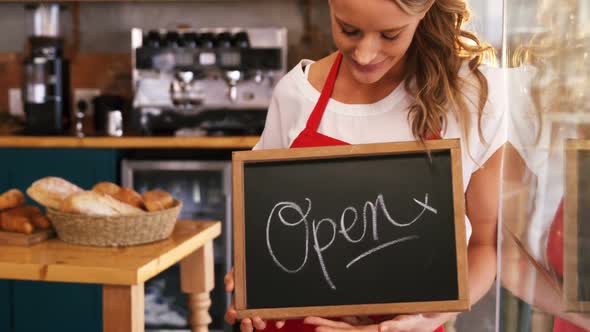 Smiling waitress holding a open sign board