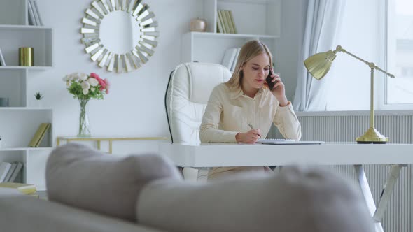 Young woman talking on the phone at home office. Working woman in a room