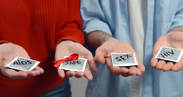 Cropped Image of Man and Woman Holding Condoms and Red Ribbon Isolated on Grey Background