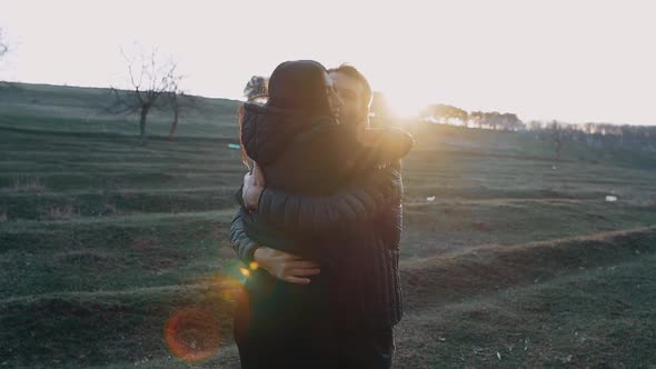 Young People in Love Embrace with Love and Kiss Affectionately in the Light of the Setting Sun