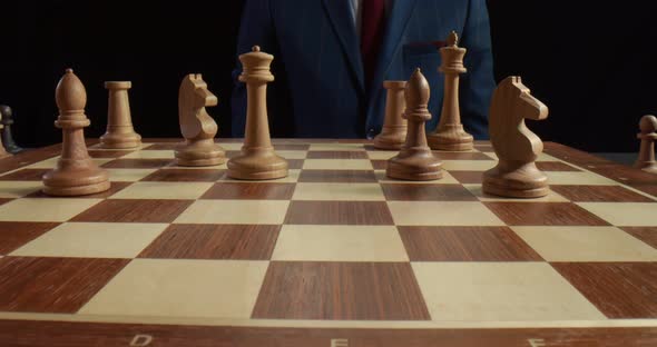 Close Up of Chess Man Player Moving White Wooden Bishop Back Isolated on Black Background