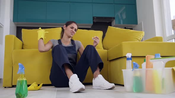 Tired Female Cleaner Sitting Near the Couch and Feeling Enfeebled After Washing Wooden Floor