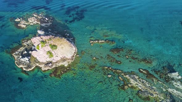 Aerial Top View Footage By Drone of Ocean Blue Water and Rocks A Calm Sea Washes the Rocky Mountain