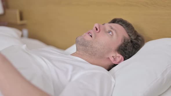 Shocked Young Man Wake Up From Sleep in Bed