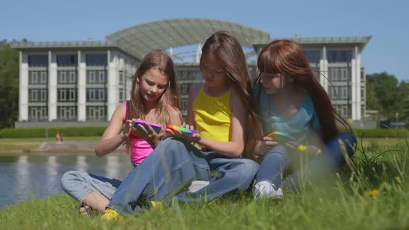 Teenage Children Playing with Pop It Fidget in Park