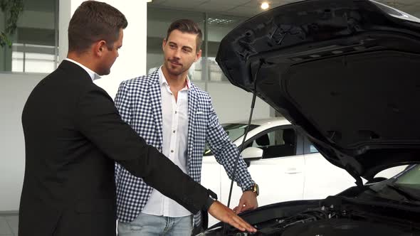 A Professional Salesman Acquaints a Buyer with a Car Engine