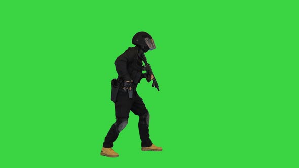 Armed Man in Protective Cask Aiming with a Pistol on a Green Screen Chroma Key