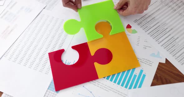 Business Team Collecting Multicolored Plastic Puzzle Pieces on Desktop