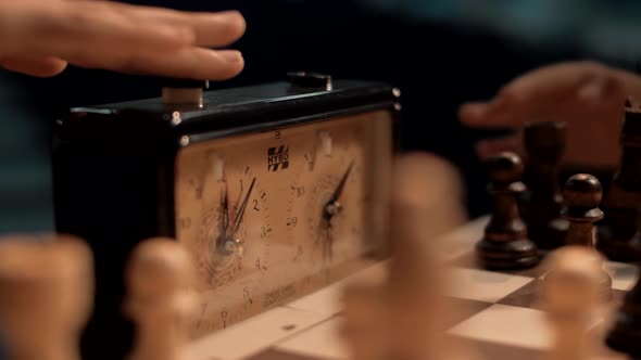 Chess players alternately press the buttons of the chess clock timer.