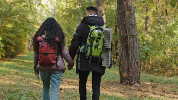 View From Back Young Married Couple in Love Hiking Tourists Walking in Forest Travel with Backpack