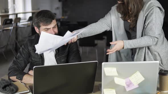 Businesswoman Throwing Papers Toward Her Collegue Showing Her Anger at the Office
