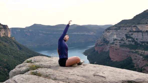 Young Hispanic sportswoman stretching body during training in rocky mountains