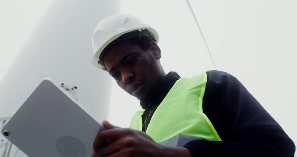 A Man in a Work Uniform is Diagnosing a Wind Turbine Using a Digital Tablet