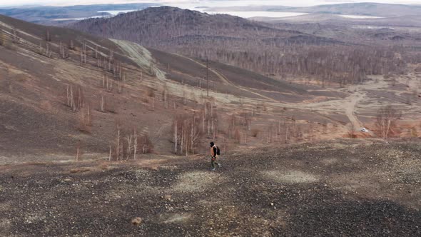 Aerial View of a Traveler Walking on a Mountain Against the Background of a Valley and Mountains