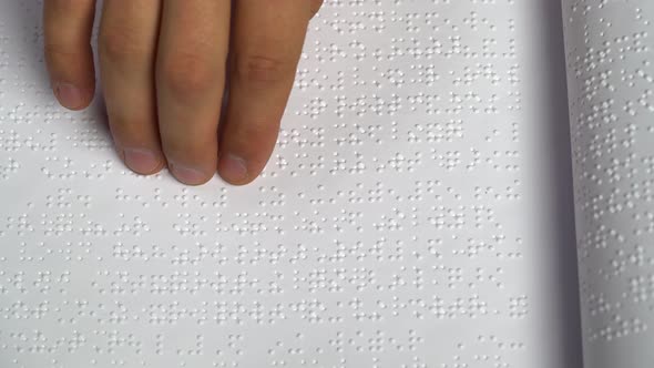 Man Learns To Read Braille on a Sheet of Paper. Close Up