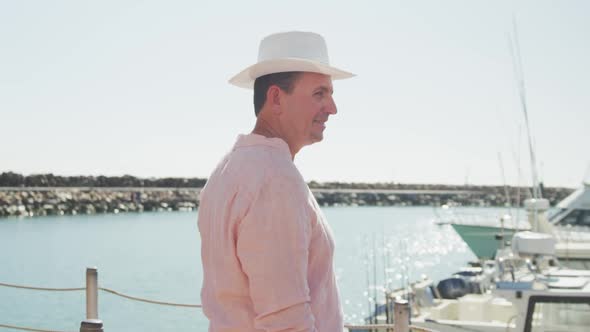 Side view of a Caucasian man enjoying harbor side and looking at camera