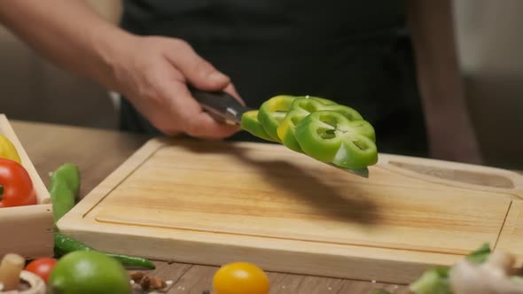 Professional chef works with green bell pepper. Close up slow motion