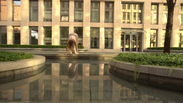 Beautiful Young Girl Dancing on the Street of a Modern City and Is Reflected in the Water