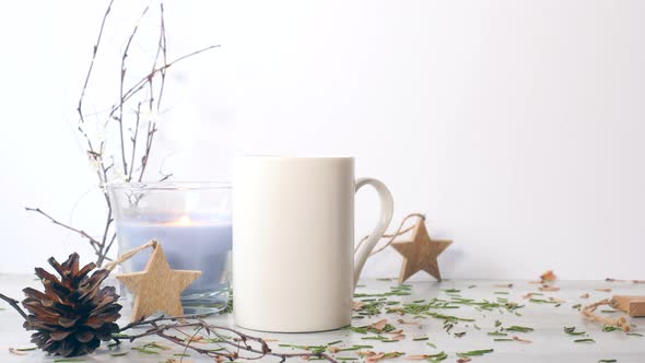 Candle Lighting Near White Ceramic Mug on the Table with Christmas Decorations