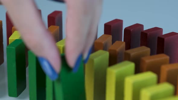 Line up of Dominoes in Rainbow Falling Colors with LGBT Colors of a Hand