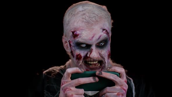 Sinister Man Halloween Zombie Enthusiastically Playing Racing Drive Video Games on Mobile Phone