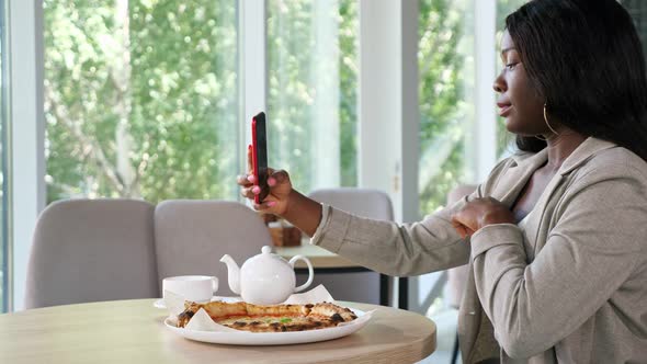 AfricanAmerican Woman Makes Selfie at Table with Pizza