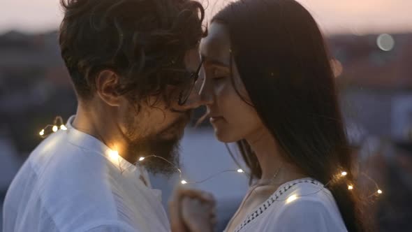 Loving Couple in Lights Bonding on Rooftop