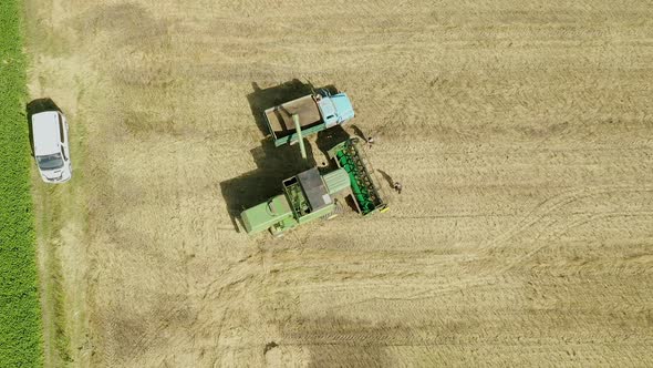 Combine harvester unloads grain to the dump truck