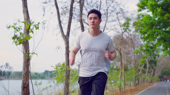 Asian young handsome active sport man running on street in public park.