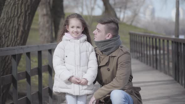 Smiling Young Caucasian Father Kissing Little Pretty Daughter on Cheek. Happy Man and Girl Spending