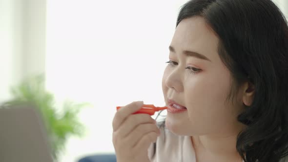 plus size Asian woman bloggers sitting are online to review cosmetic products via social media.