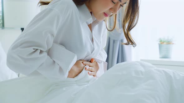 Woman feel bad and painful after wake up on bed, having stomach ache or periods then clasping belly