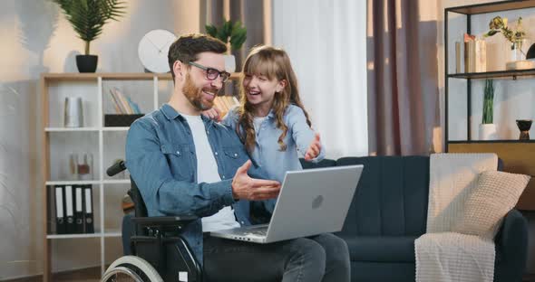 Disabled Dad in Wheelchair Having fun Together with His 10-aged Daughter while Using Computer