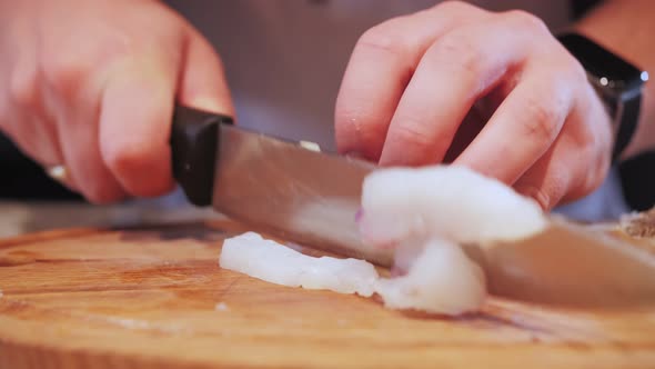 fish fillet is cut with a knife on a kitchen board