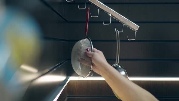 Woman Takes Fine Sieve Hanging on Kitchen Organizer