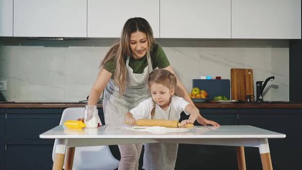 Mother and Little Daughter Smile in Kitchen While