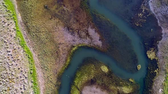 Top down aerial view of colorful river flowing into lake