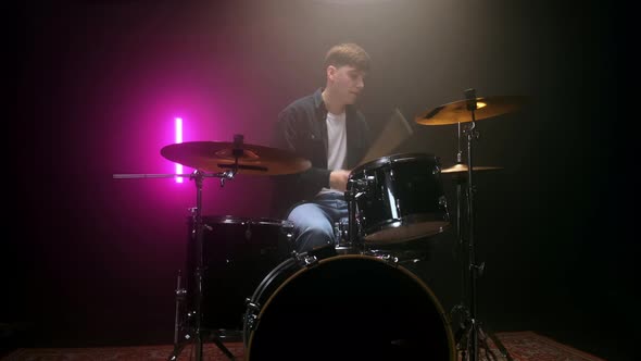 Drummer Playing the Drum Set in a Dark Room on a Black Background