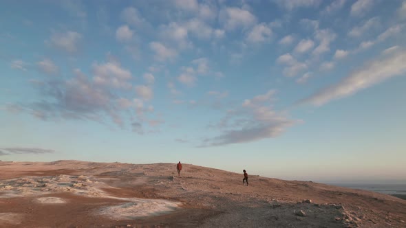 Two Tourists Walking in Vast Geothermal Field Under Majestic Bright Sky