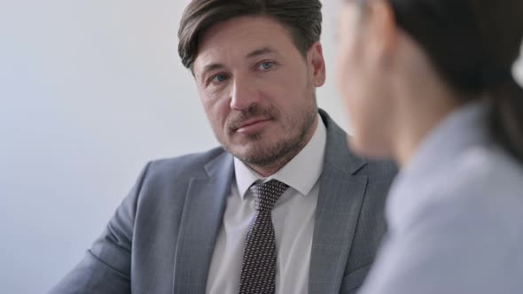 Attractive Middle Aged Businessman Listening to Female Colleagues in Office e
