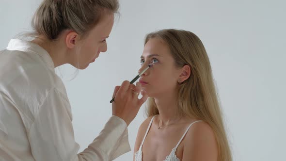 Young Makeup Artist Doing Makeover To Pretty Model