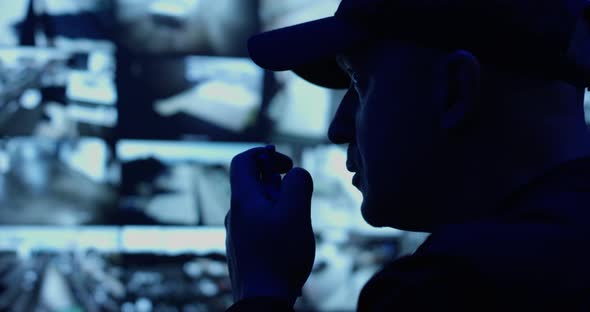 Male Officer Sits in a Control Room in front of a Surveillance CCTV Video