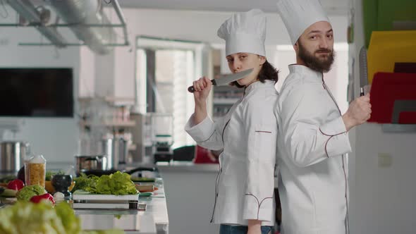 Portrait of Chefs Team Acting Funny with Knives in Restaurant Kitchen