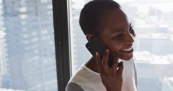 Portrait of smiling african american businesswoman having call at window