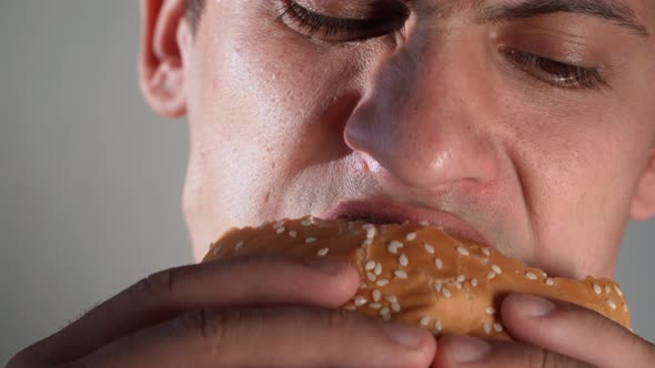 The Man Is Eating a Hamburger. Junk Food. Unhealthy Eat Habits. Close-up.