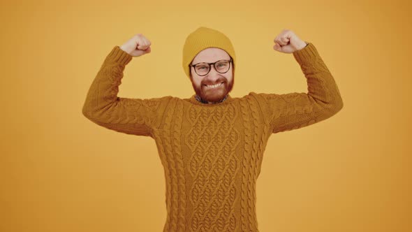 Funny Millennial Caucasian Unshaved Hipster Tightening His Muscles and Grinning at Camera Yellow