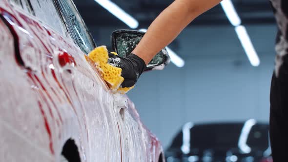 Auto Cleaning Service  Man Cleaning the Car Surface with a Yellow Sponge