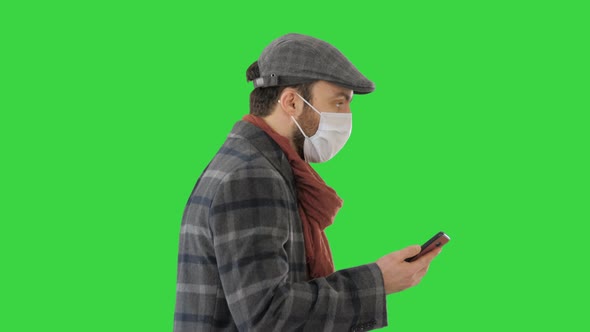 Adult Man Wears Protective Medical Mask Talking on the Phone and Walking on a Green Screen, Chroma